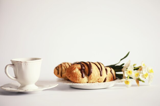 Französisches Frühstück auf dem Tisch. Kaffeecroissant mit Schokolade und einer Karaffe mit Sahne. Frisches Gebäck und entkoffeinierter Kaffee.