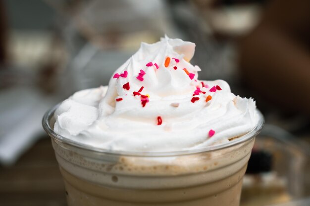 Frapuccino-Plastikglas mit Schlagsahne und bunten Schokoladensplittern darauf. Kühles, gefrorenes Getränk