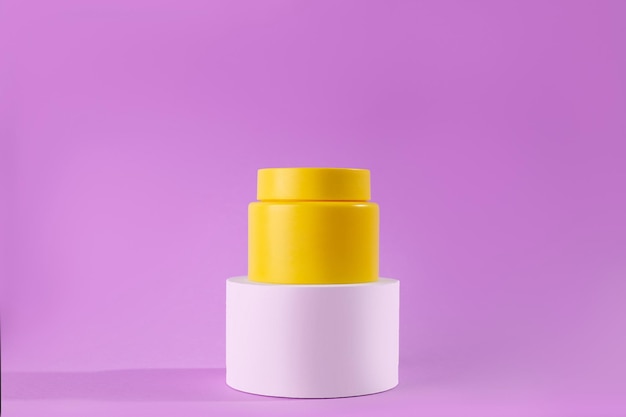 Frasco amarelo de creme em um pódio branco sobre um fundo roxo Olhar elegante o produto simulado