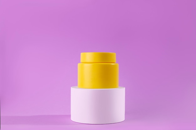 Frasco amarillo de crema en un podio blanco de pie sobre un fondo púrpura Aspecto elegante maqueta del producto