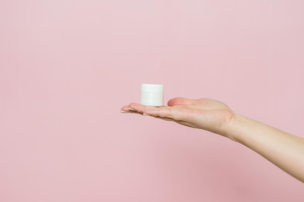 Foto frasco blanco o tubo con ungüento de crema en la mano frasco de cuidado facial con producto cosmético sin etiquetar
