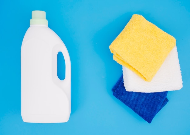Frasco branco detergente perto do guardanapo multi colorido sobre fundo azul