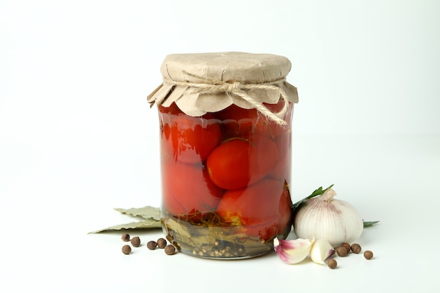 Frasco com tomate em conserva e ingredientes em fundo branco