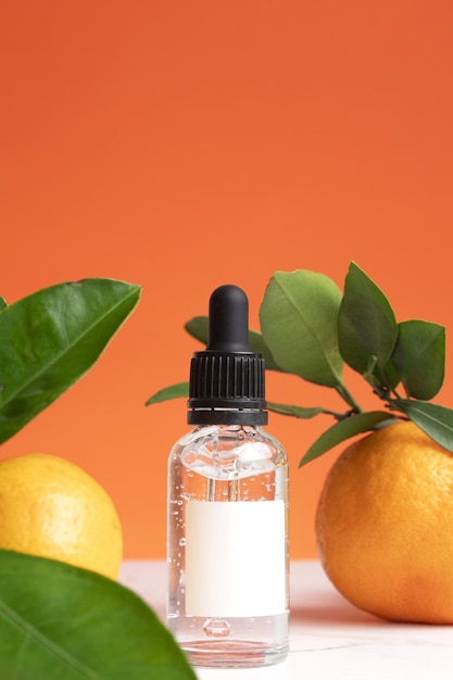 Frasco conta-gotas com maquete de etiqueta branca Hidratante aromaterapia tratamento de desintoxicação efeito anti-stress Frutas frescas folhas verdes fundo laranja