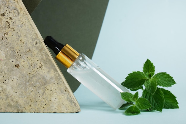 Frasco conta-gotas e folhas de hortelã, óleo de hortelã em cosméticos, frasco com pipeta, uso de óleo de hortelã em aromaterapia e cosméticos