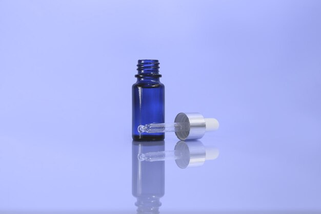 Foto un frasco cosmético con cuentagotas de vidrio en el fondo azul.