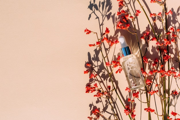 Frasco cosmético con flores rojas de suero