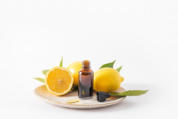 Frasco cosmético hecho de vidrio oscuro con aceite de limón orgánico, un suero a base de aceite esencial para la cosmética vegetal para el cuidado de la piel facial