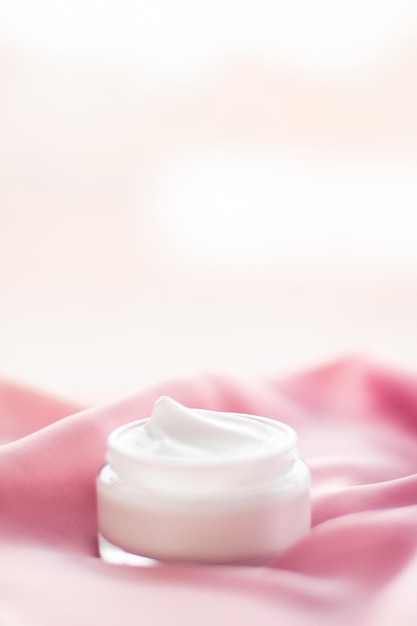 Frasco de crema facial de lujo en una seda rosa suave