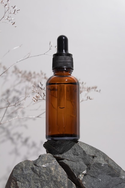 Frasco cuentagotas de vidrio ámbar con una pipeta sobre piedras fondo gris Concepto de cosmética natural aceite esencial natural