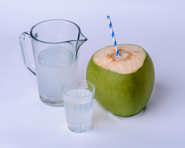 Foto frasco de copo de água de coco e coco verde no fundo branco