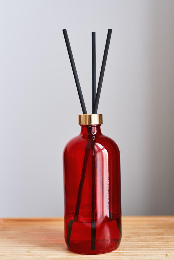 Foto frasco de difusor de fragrância de quarto com três varas em uma bandeja de madeira