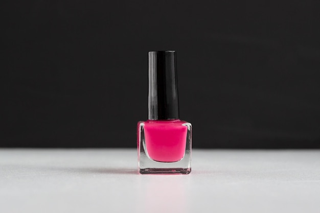 Frasco de esmalte rosa em fundo preto e branco