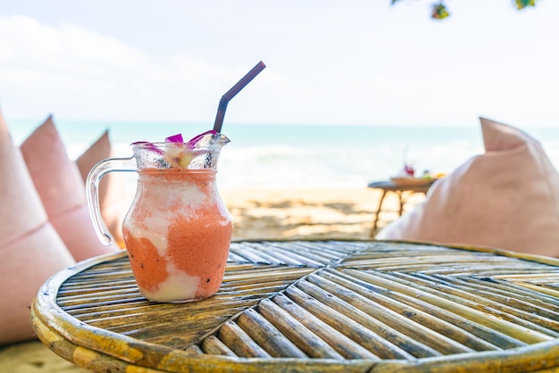 Foto frasco de manga, abacaxi, melancia e iogurte ou smoothies de iogurte com praia de mar