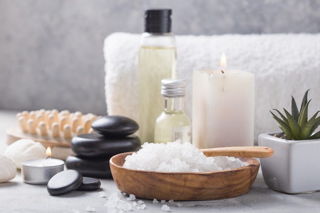 frasco de óleo de massagem de aroma essencial e natural sal de fragrância com pedras, velas na mesa de concreto cinza.