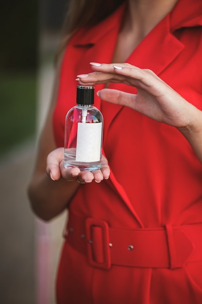 Frasco de perfume de uma mão feminina. Jovem mulher elegante segurando um frasco de perfume. Perfume da moda nas mãos de mulheres. Perfume de pulverização de menina. Lindas mãos femininas. Perfumes para mulheres