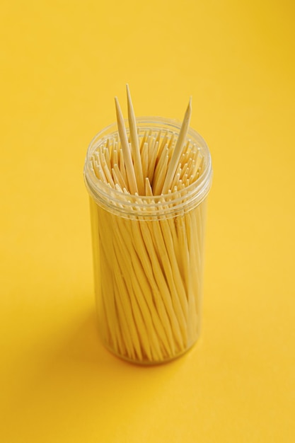 Foto frasco de plástico com palitos de bambu de madeira fica em um fundo amarelo