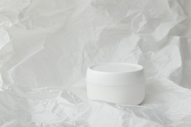 Frasco de plástico redondo branco para maquete de creme cosmético em fundo de papel amassado branco