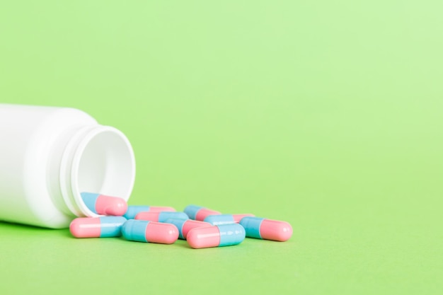 Frasco de remédio de plástico com cápsulas de comprimidos em fundo colorido Farmácia on-line Medicina analgésica e conceito de resistência a antibióticos Indústria farmacêutica