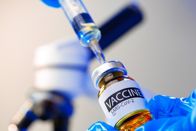 Frasco de vacina Covid-19 com uma seringa retirando a vacina dele