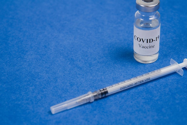 Frasco de vacina Covid19 e seringa para injeção em um tratamento de vacinação SARSCoV2 de fundo azul