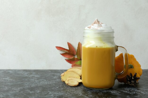 Frasco de vidro com café com leite de abóbora e ingredientes na mesa preta esfumada