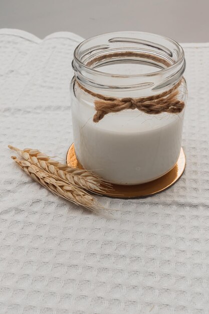 Foto frasco de vidro com leite vegano, trigo. ingredientes para fazer produtos lácteos alternativos.