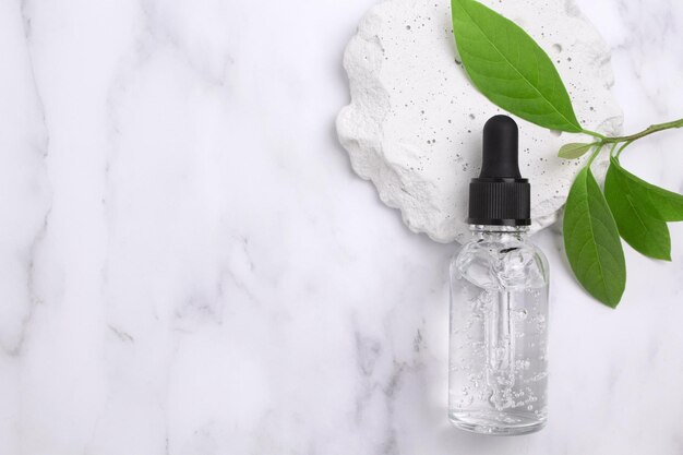 Frasco de vidro cosmético com conta-gotas e folhas verdes no pódio O conceito de salão de beleza e cosméticos naturais