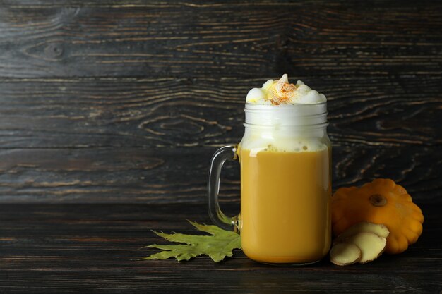 Foto frasco de vidro de café com leite de abóbora e ingredientes em fundo de madeira rústico