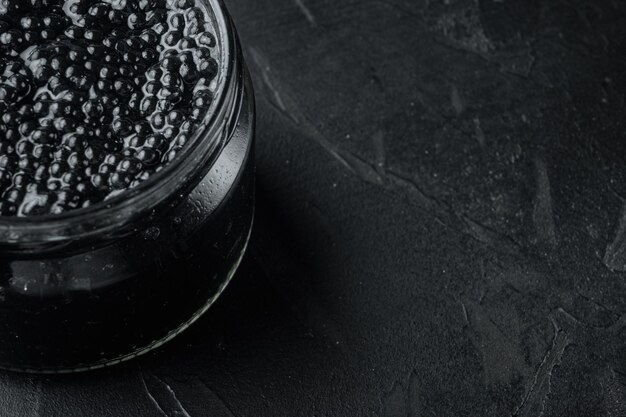 Frasco de vidro de caviar preto, na mesa preta