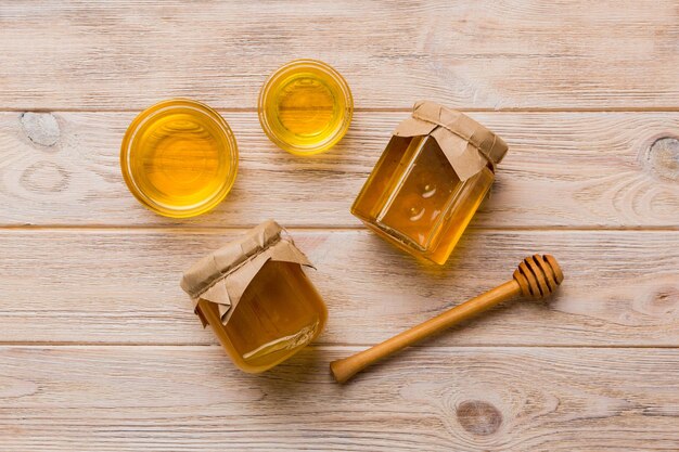 Frasco de vidro de mel com chuvisco de madeira sobre fundo colorido Pote de mel e concha acima do espaço de cópia da vista superior