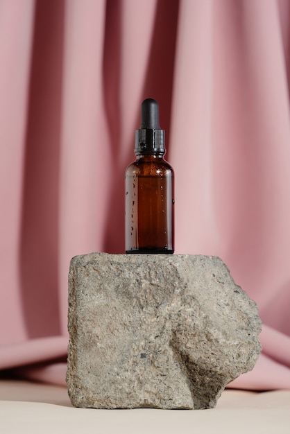 Frasco de vidro de óleo natural ou soro em maquete de cosméticos neutros de tijolo de pedra