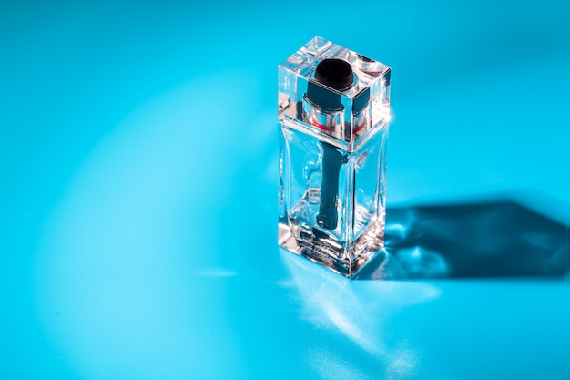 Frasco de vidro de perfume sobre fundo azul claro. Eau de toilette