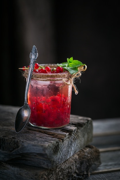 Frasco de vidro de refrigerante de groselha na mesa de madeira escura