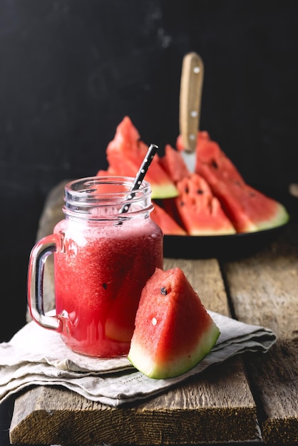 Frasco de vidro de saboroso smoothie de melancia em fundo de madeira vertical saudável e saborosa bebida de verão