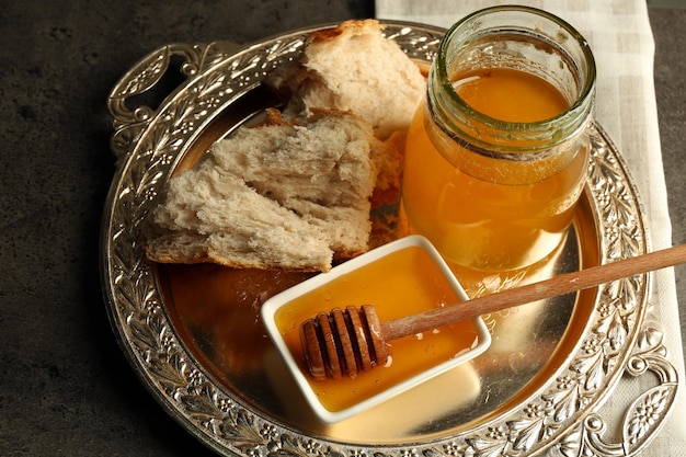 Frasco de vidro e tigela com mel e nozes em fundo cinza