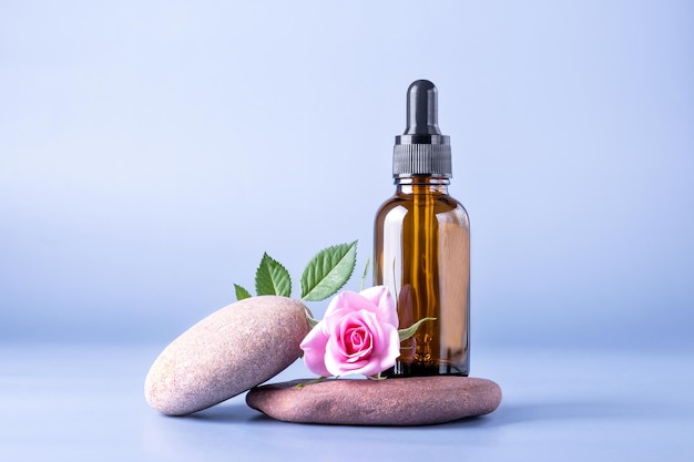 Frasco de vidro marrom com uma pipeta para um produto cosmético com uma rosa em pedras Cosméticos naturais para cuidados com a pele do rosto e corpo Foco seletivo