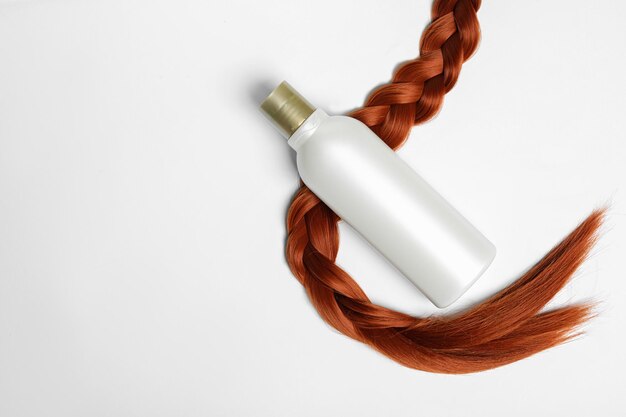Foto frasco em branco de produto cosmético e cabelo trançado na vista superior de fundo branco espaço para design