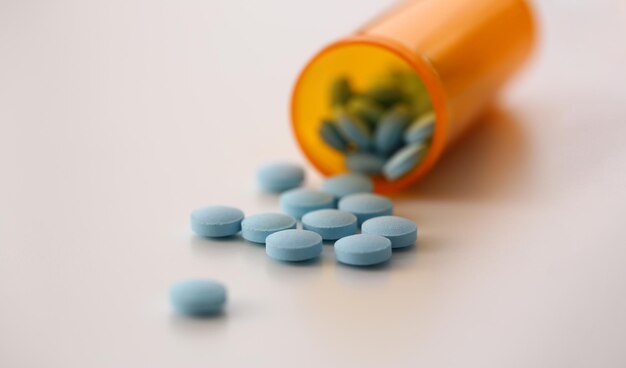Frasco de pastillas azul redondo médico con pastillas en la mesa