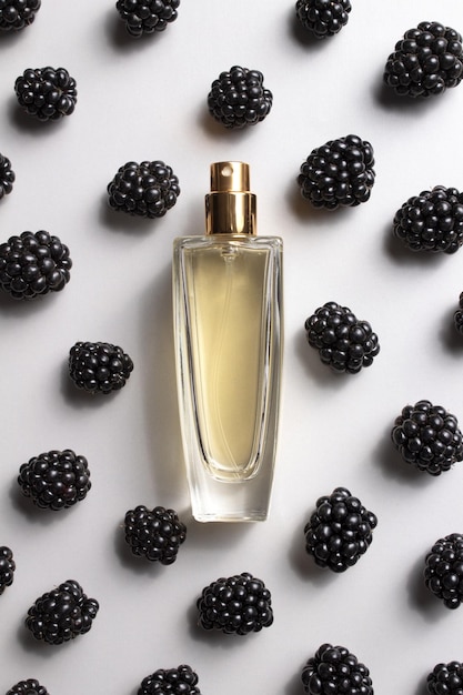 Frasco de perfume con moras Concepto de perfumes y cosméticos caros Esencia de mujer