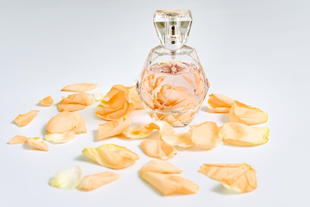 Frasco de perfume con pétalos de flores sobre fondo claro. Perfumería, colección de fragancias. Accesorios de mujer.