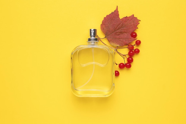 Frasco de perfume y una rama de viburnum maduro de otoño Concepto de perfumes y cosméticos caros Fragancia de bayas para mujeres Aerosol de perfume