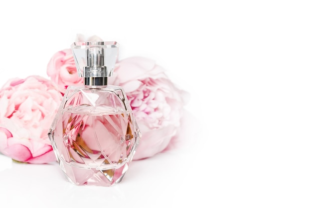 Frasco de perfume rosa con flores en superficie clara