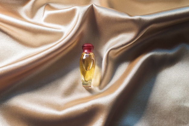 .Frasco de perfume sobre fondo de tela de seda dorada dorada. Producto de belleza cosmético con fragancia Luxery Scent.
