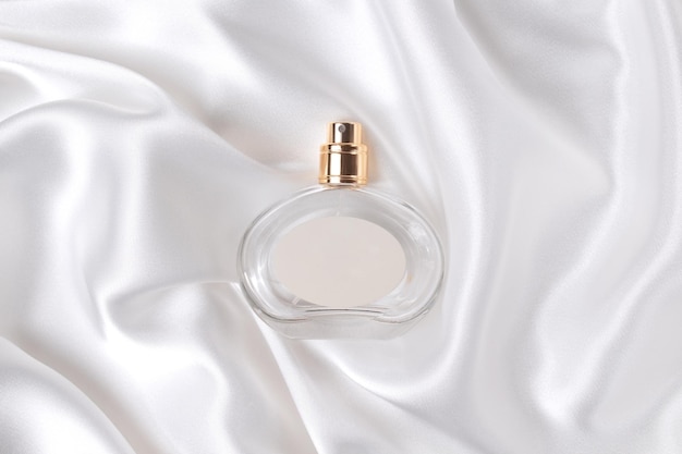 Frasco de perfume de vidrio sobre una seda blanca el concepto de perfume y cosméticos caros