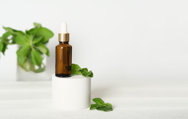 Frasco de pipeta cuentagotas de vidrio ámbar en un podio con hojas de plantas, serum cosmético natural, cuidado antiedad y arrugas, péptido de colágeno y cuidado de ácido hialurónico.