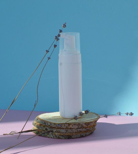 Un frasco de plástico blanco se encuentra sobre un podio de madera con flores de lavanda secas Una maqueta de un cosmético s