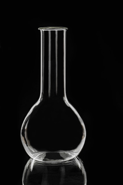 Frasco químico de vidro de laboratório em um fundo preto. Equipamento de laboratório.