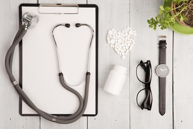 Foto frasco de reloj de vidrio con almohadilla de estetoscopio de concepto médico y corazón blanco de píldoras y cápsulas