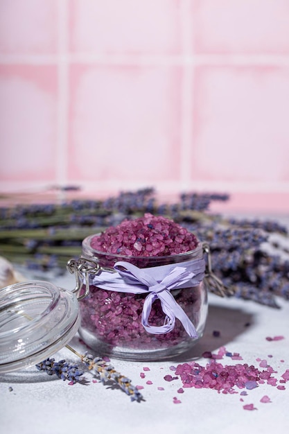 Un frasco de sal de baño púrpura con toalla de lavanda y velas foto vertical